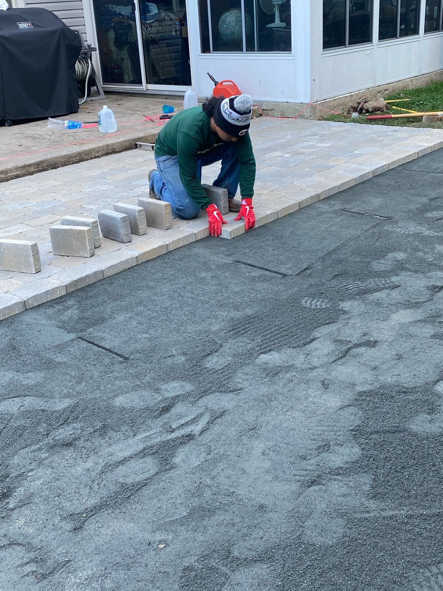 Installer setting rectangular cobble pavers by hand
