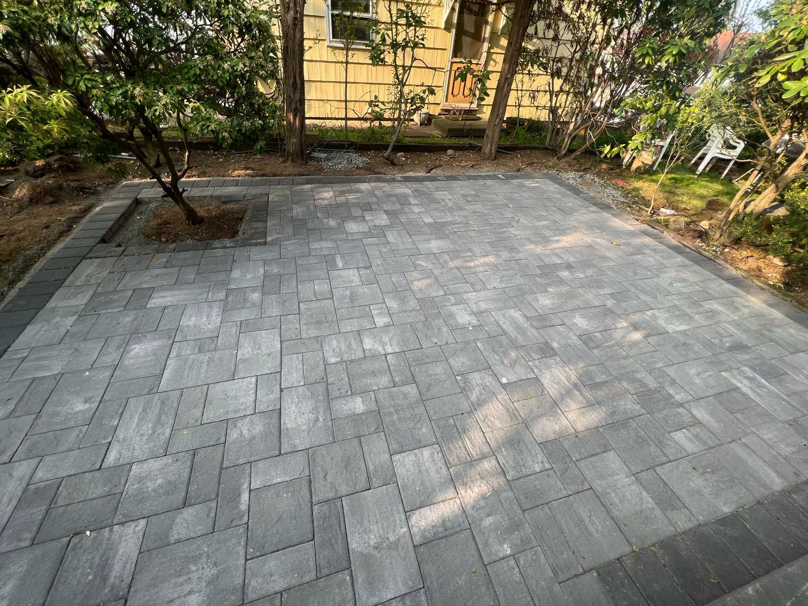 Charcoal paver patio with tree pocket and soldier course border